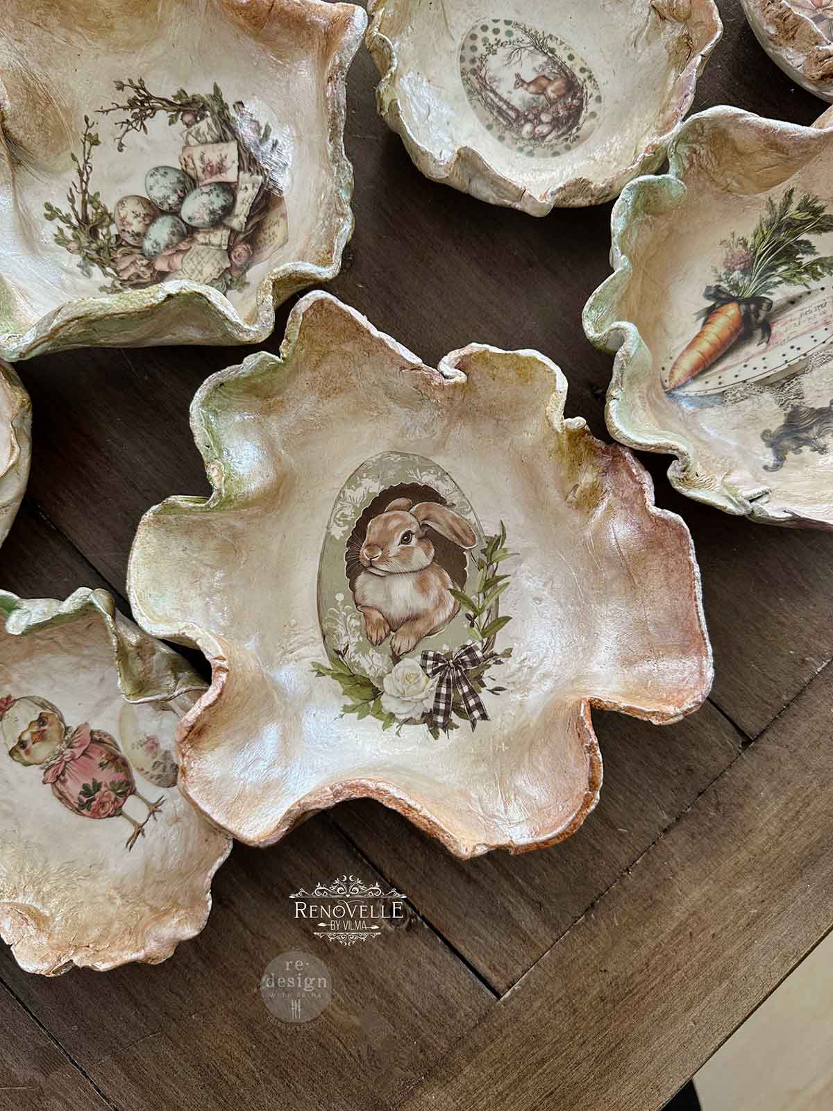 Decorative ceramic oyster shells with artistic designs on a wooden surface, featuring the brand 'Renovelle'.