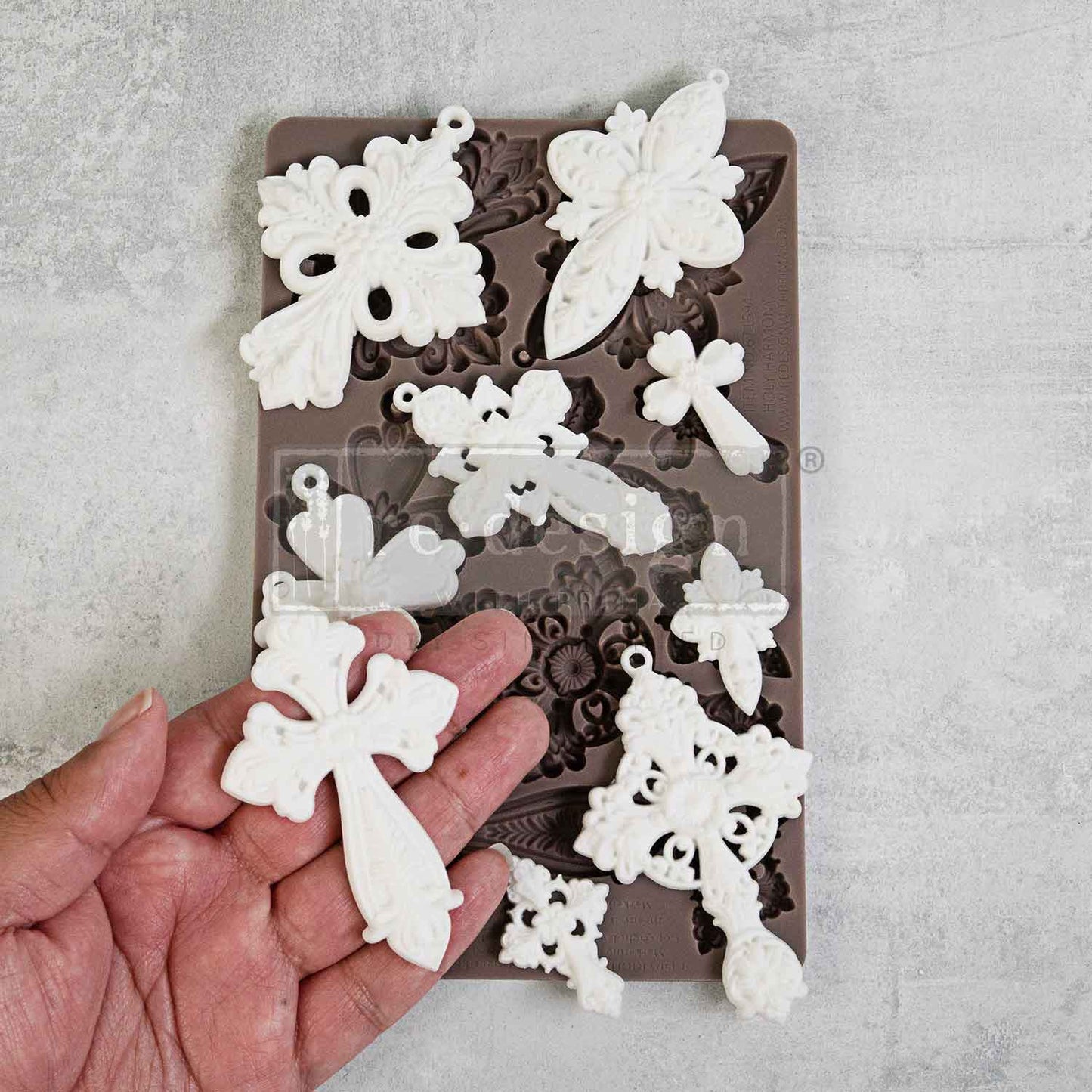 Silicone mold with white floral and butterfly shapes on a gray background