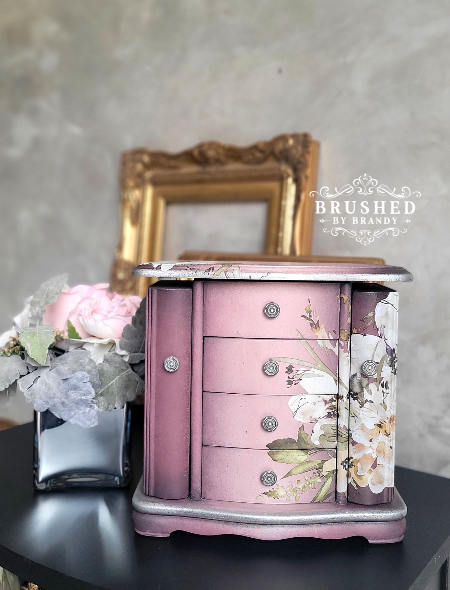 Pink jewelry box with floral design on a dark surface, with 'Brushed by Brandy' branding.