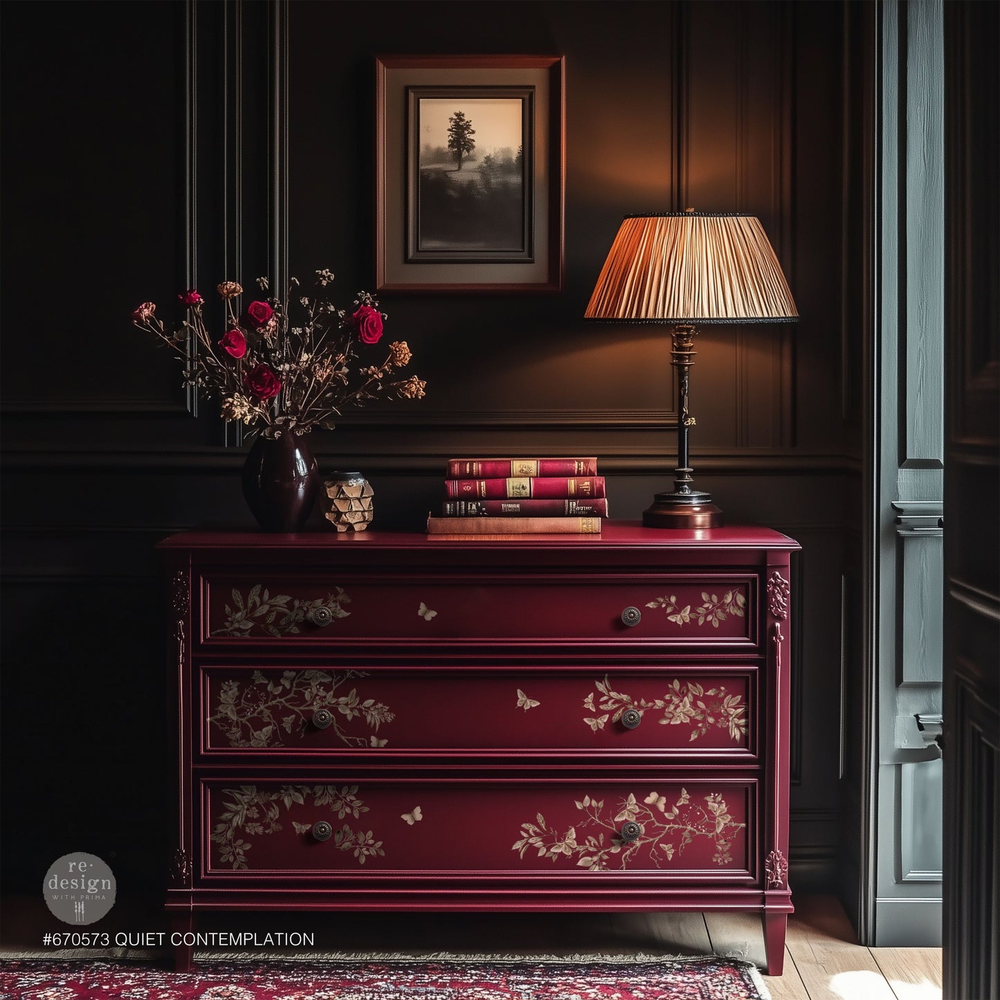 Red dresser with floral patterns in a darkly decorated room with a lamp and books.