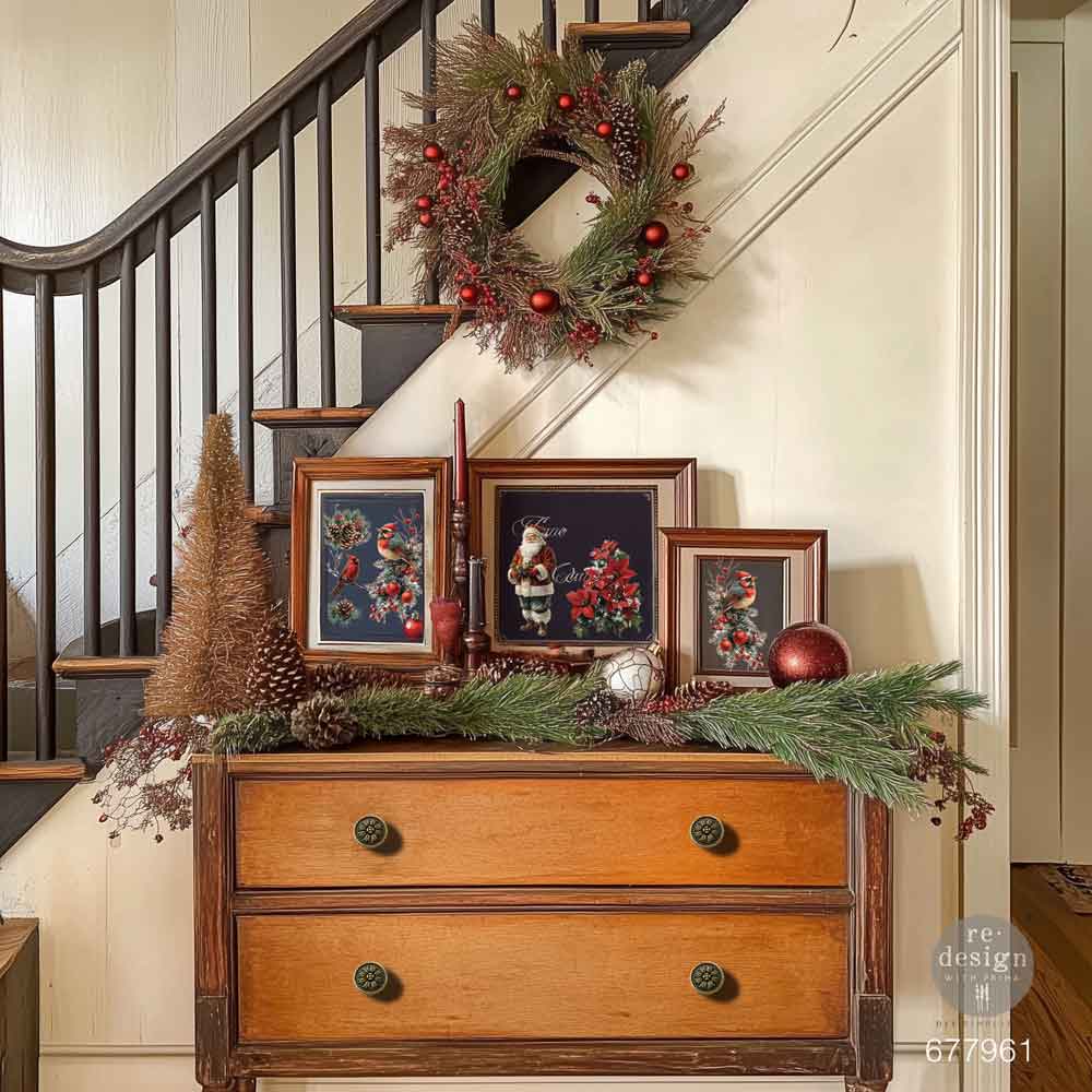 Decorative setup with a wreath, framed pictures, and a wooden dresser in a home interior.