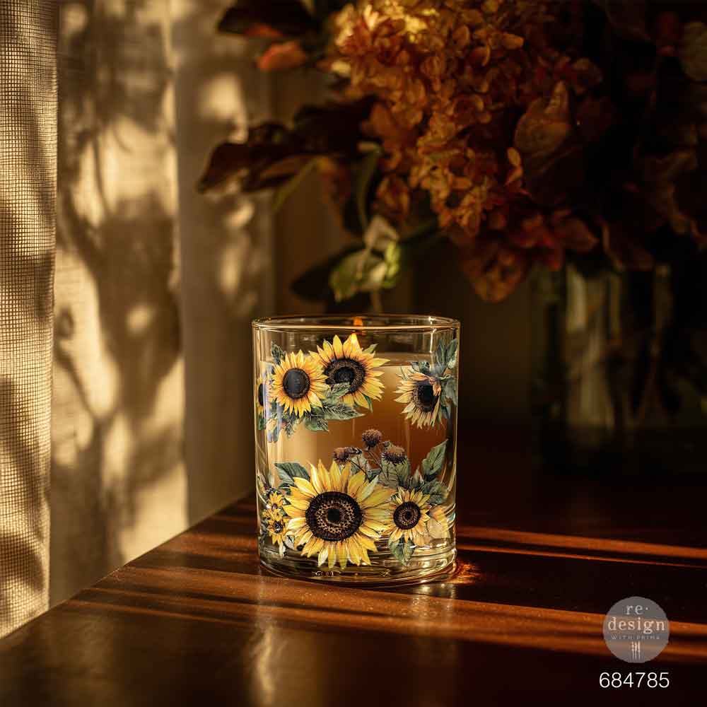 Glass tumbler with sunflower design on a wooden surface with a blurred background