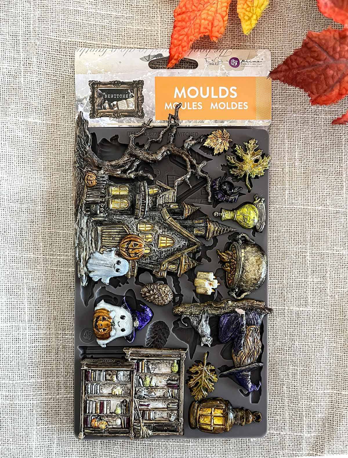 Halloween-themed moulds set on a textured surface with autumn leaves.