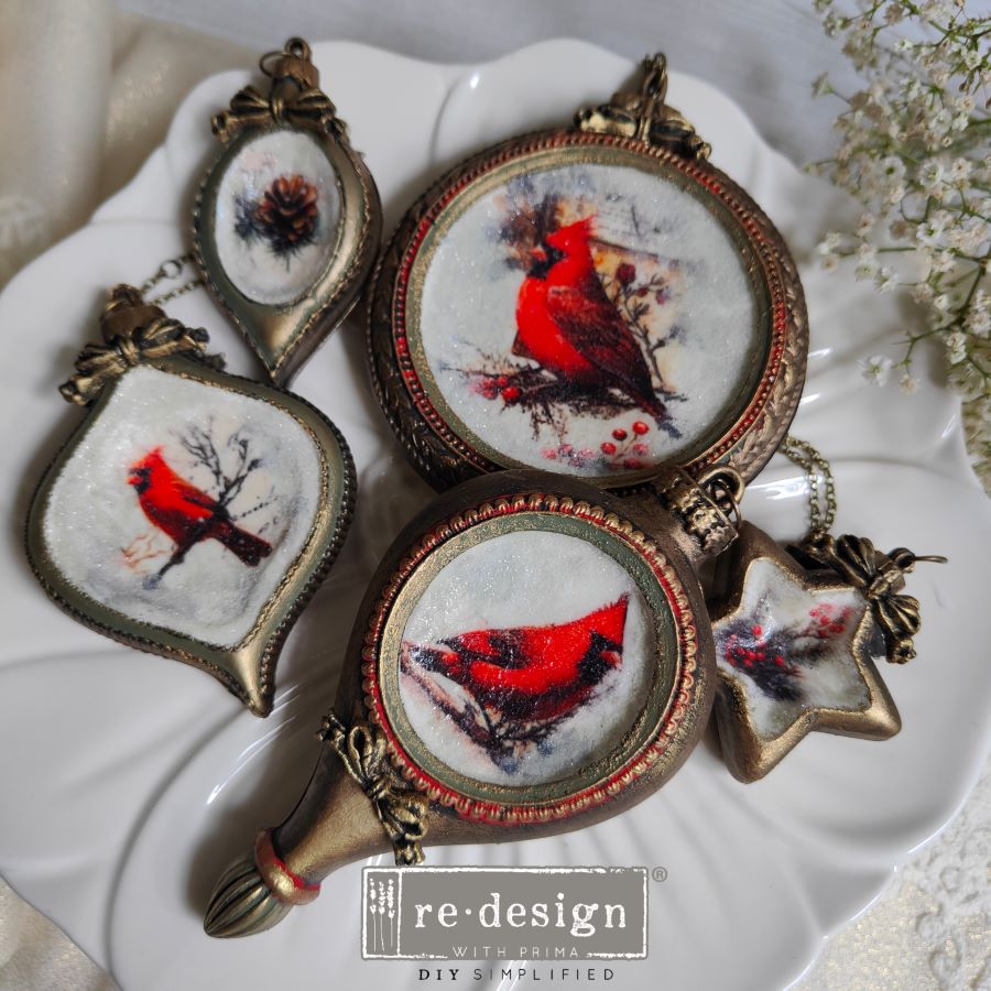 Decorative pendants with red cardinal designs on a white plate.