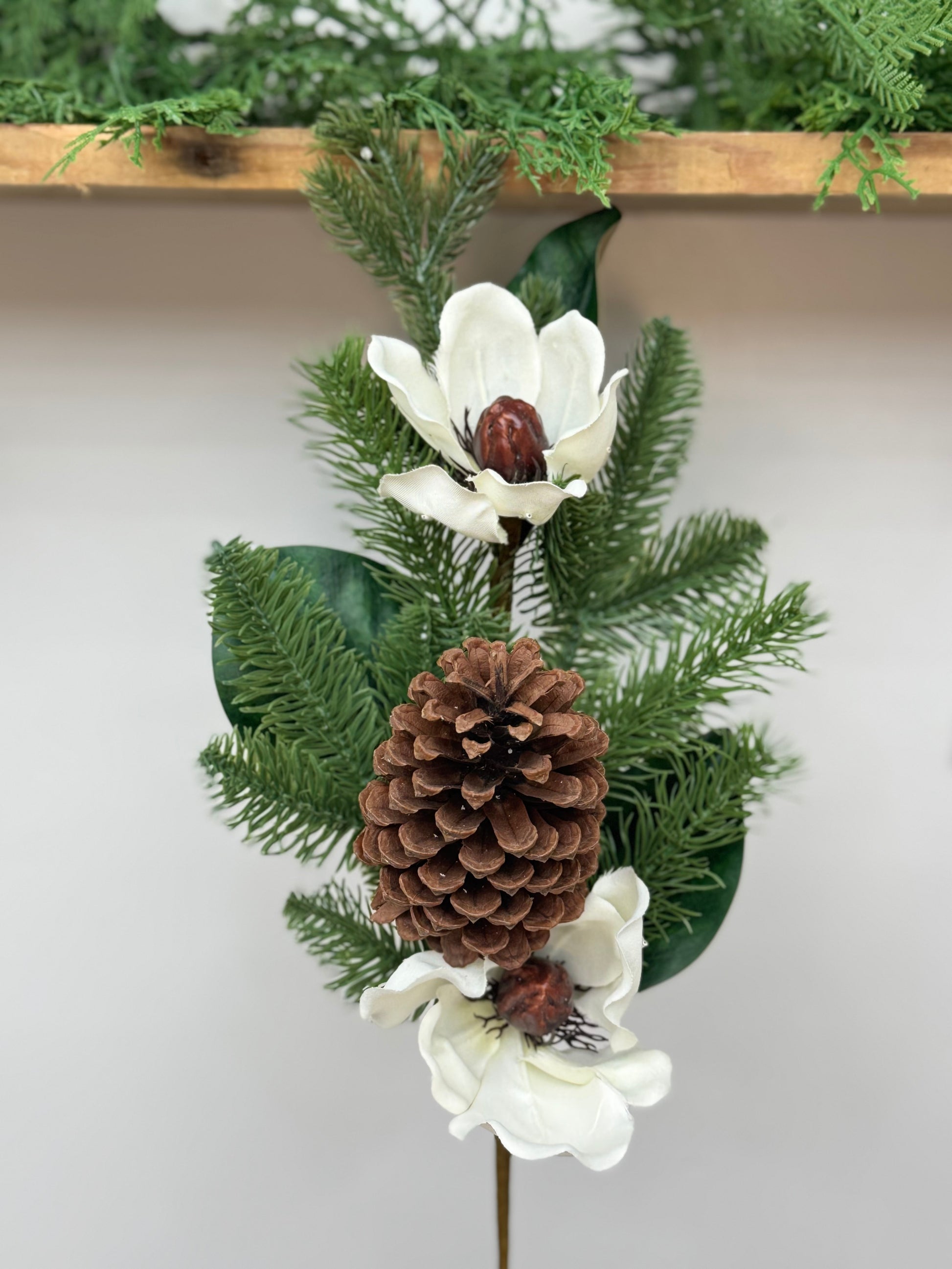 Magnolia pick with real feel pine branches, magnolia leaves, magnolia blooms, and pinecone.