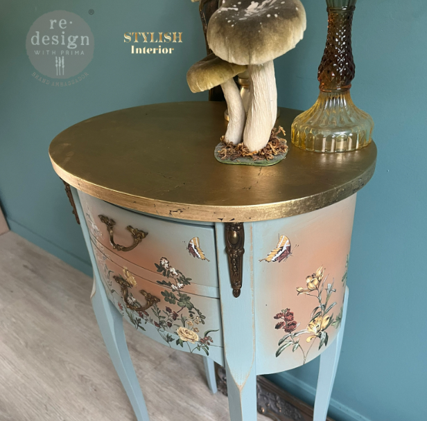 Decorative chest of drawers with floral patterns and a gold top against a blue wall.