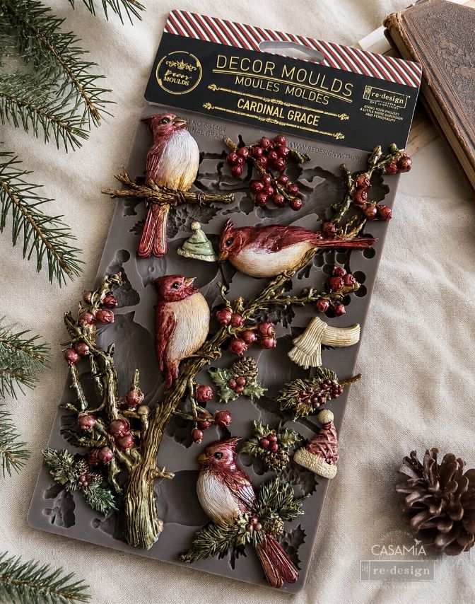 Decorative mold with cardinal birds and berries on a textured surface with pine branches.