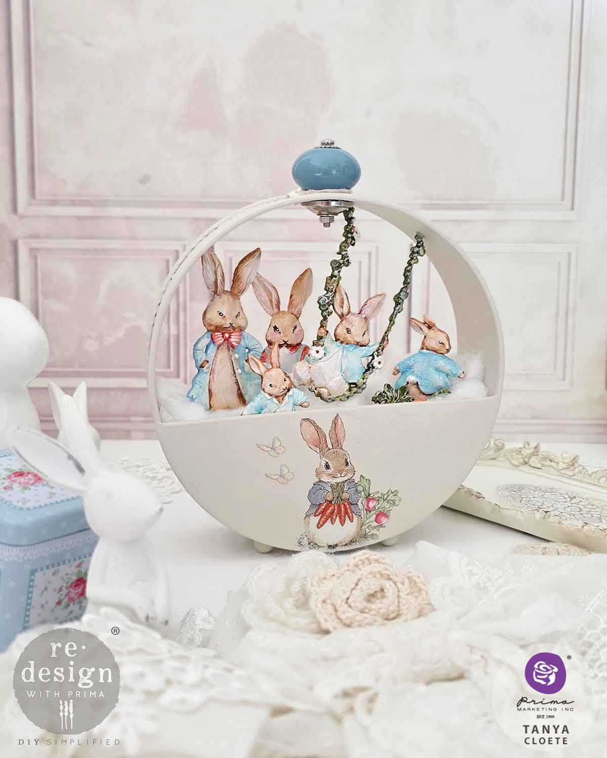 Decorative item with rabbit figures on a swing against a light pink wall.