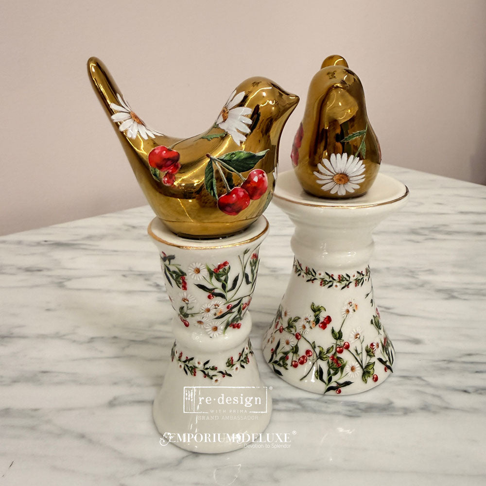 Decorative salt and pepper shakers with floral and berry design on a marble surface.