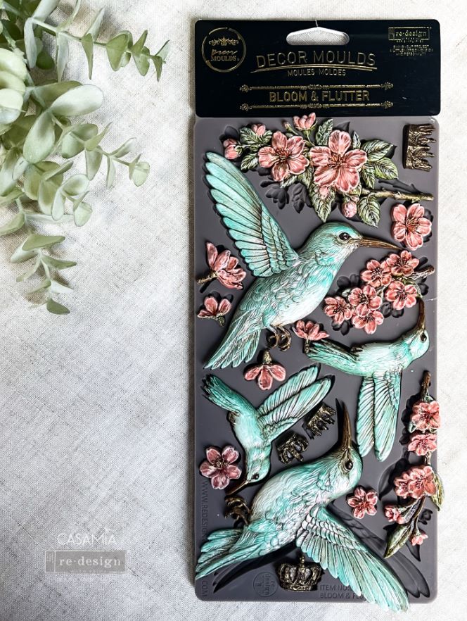the humming bird castings painted aqua and pink sitting on top of the silicone mould