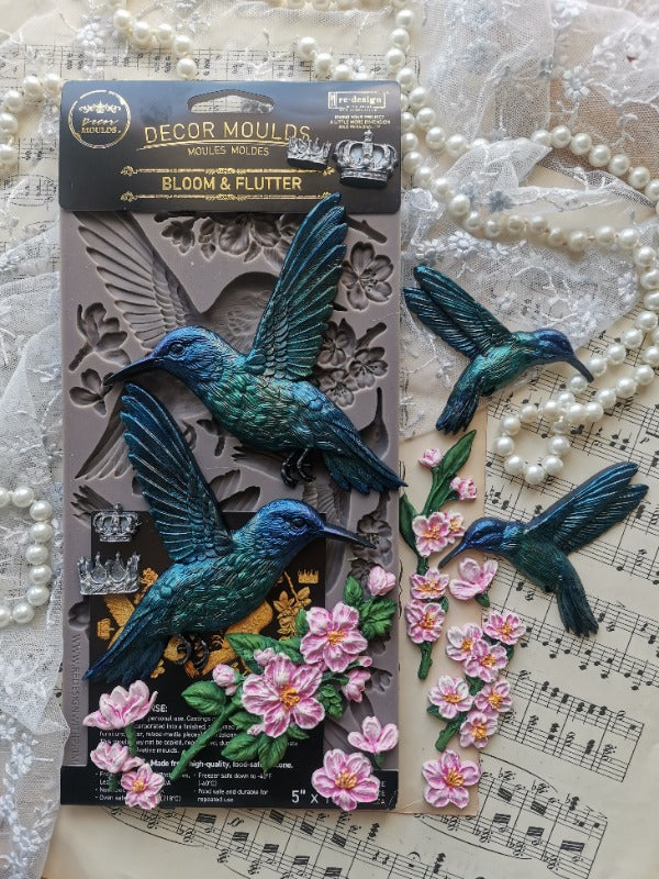 the humming bird castings painted blue and pink sitting on top of the silicone mould