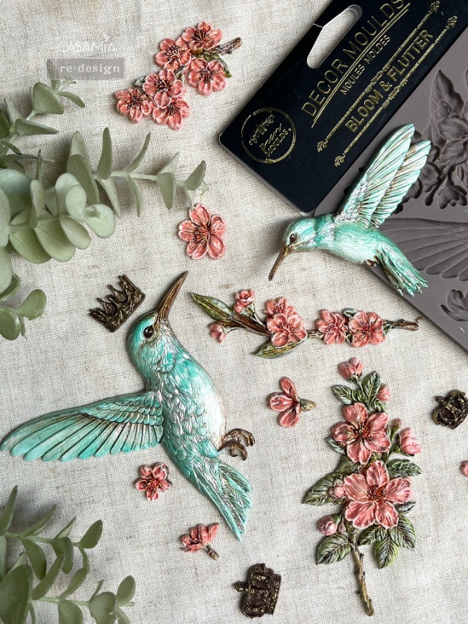 the humming bird castings painted aqua and pink sitting on top of the silicone mould
