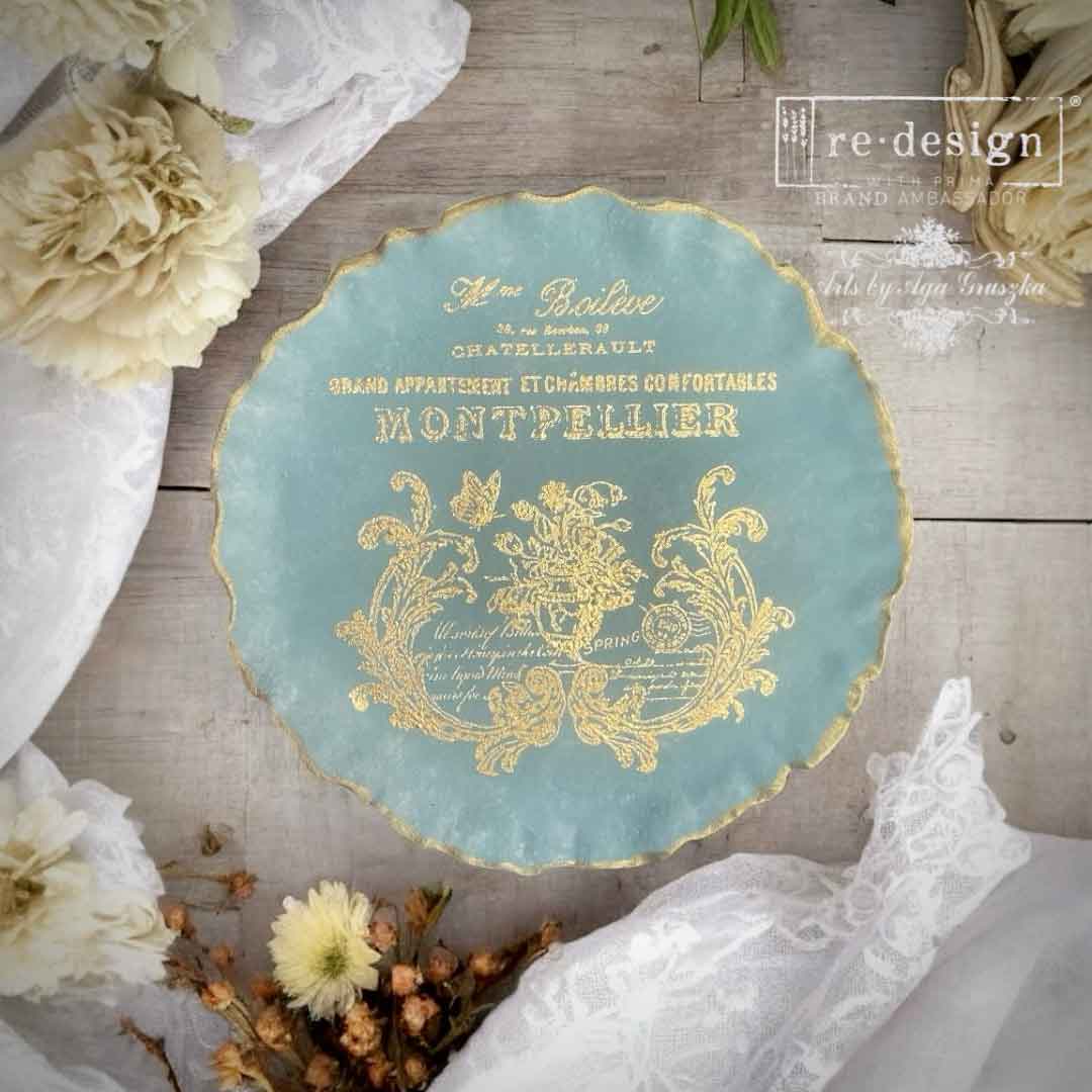 Decorative plate with gold text and design on a wooden surface with flowers