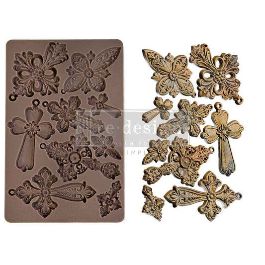 Decorative metal mold with intricate designs and corresponding metal embellishments on a white background.