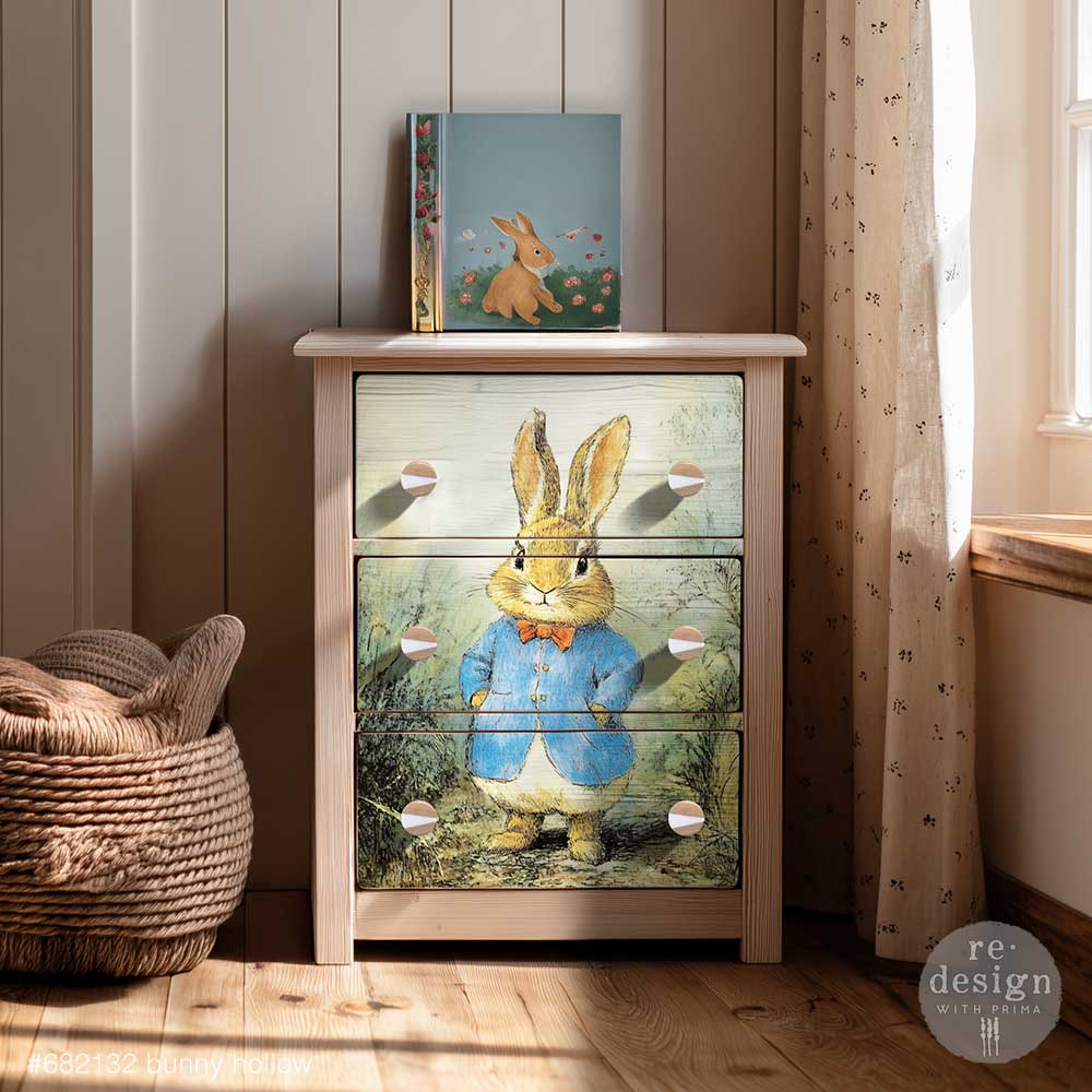 Wooden dresser with rabbit design on drawers in a room with a basket and book.