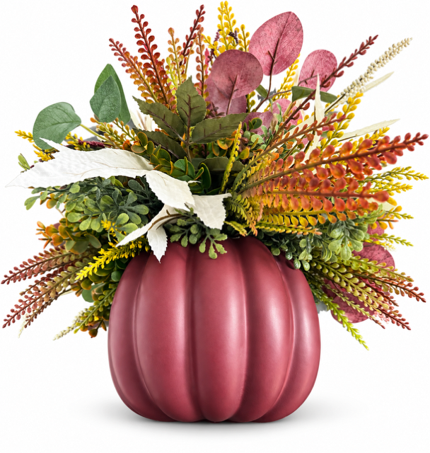 An autumn floral arrangement featuring a ribbed burgundy pumpkin vase filled with faux green, yellow, orange, and burgundy foliage, set against a plain white background.