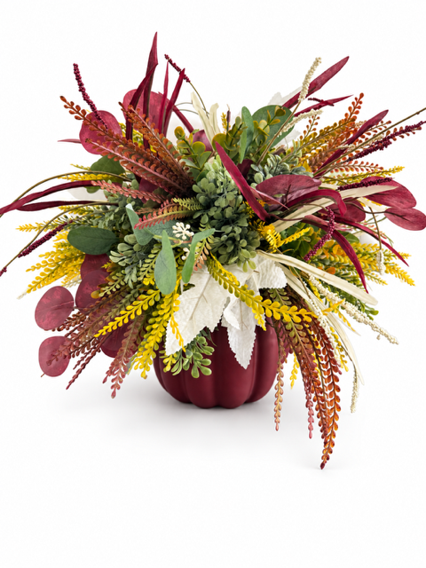An autumnal floral arrangement in a dark burgundy pumpkin-shaped vase, featuring burgundy, yellow, green, and white foliage on a clean white background.