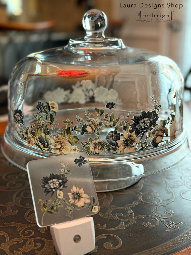 Glass cloche with floral design on a decorative surface, featuring 'Laura Designs Shop' branding.