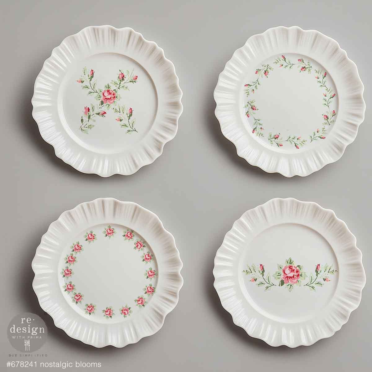 Four white decorative plates with floral patterns on a gray background