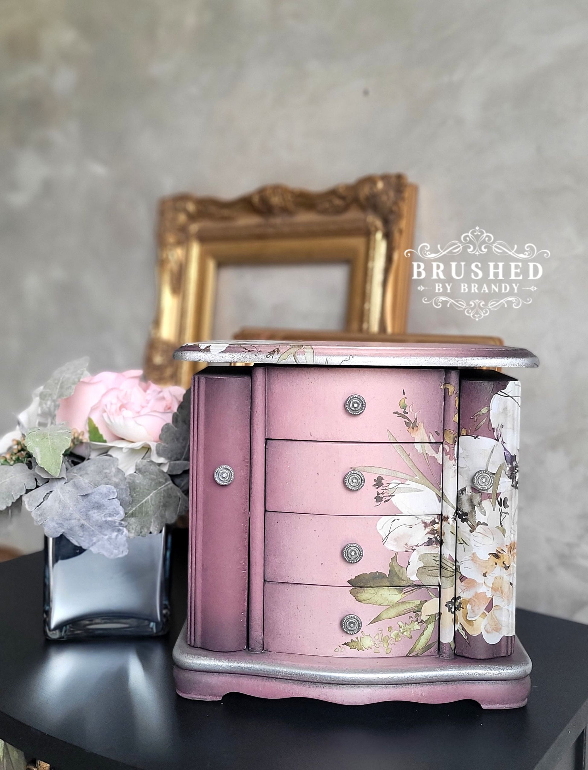 Pink jewelry box with floral design on a dark surface, with 'Brushed by Brandy' branding.