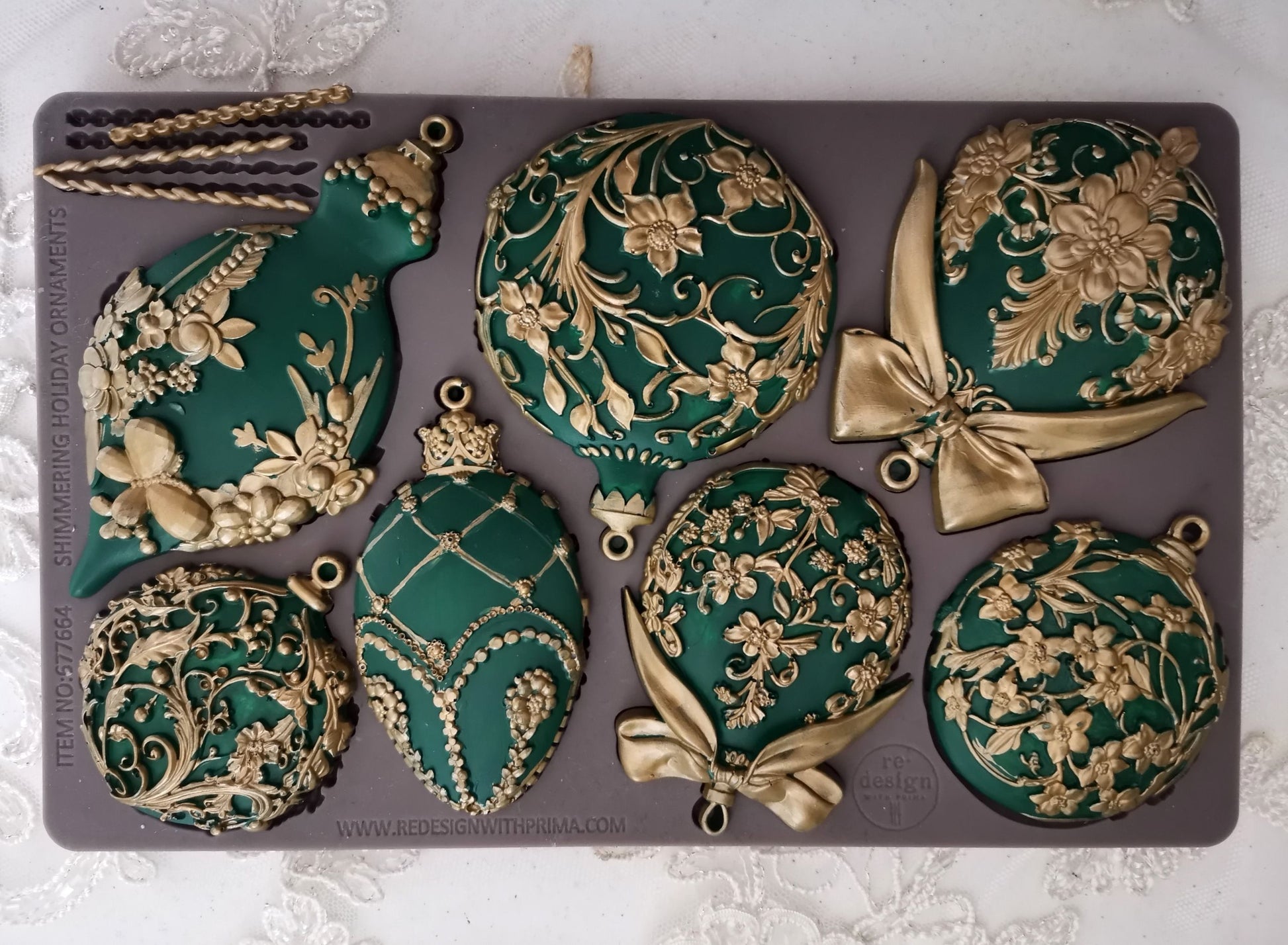 Decorative green and gold Christmas ornaments on a gray silicone mold.