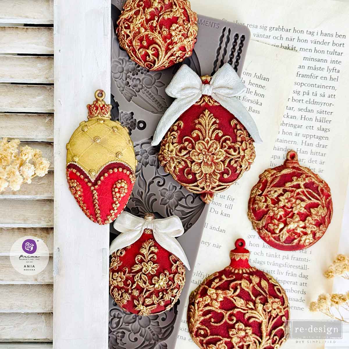 Decorative Christmas ornaments with red and gold designs on a book page.