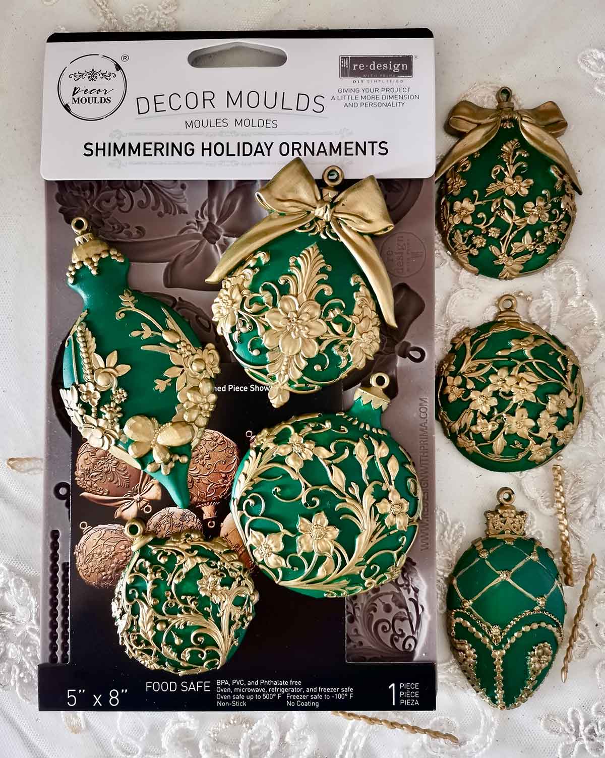 Decorative mold set for making green and gold ornaments on a white lace background