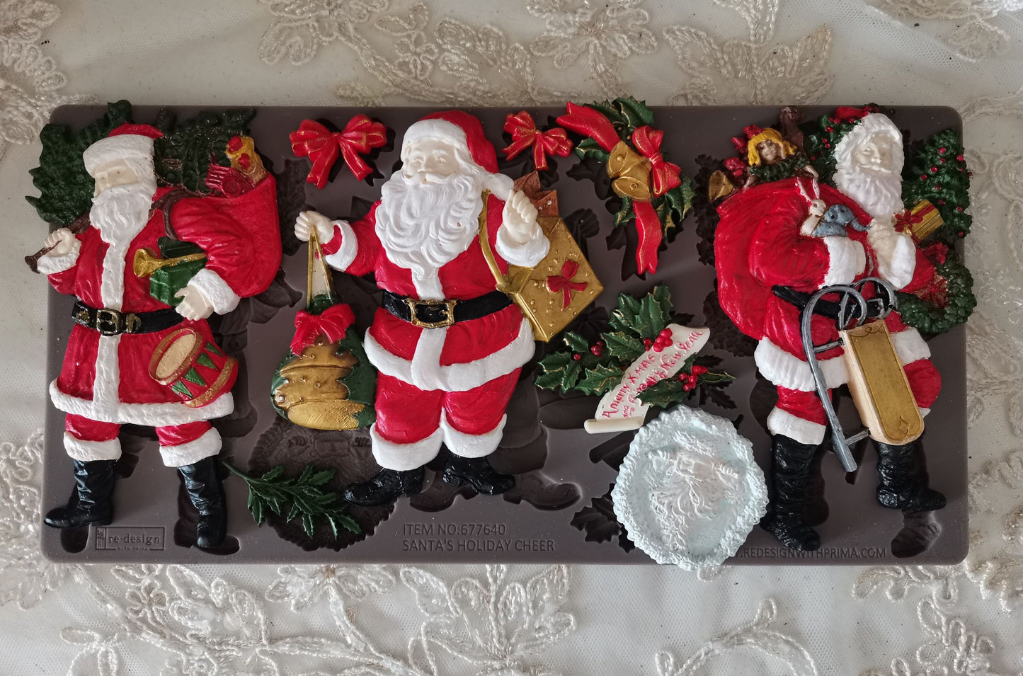 Chocolate mold with three Santa Claus figures on a decorative surface