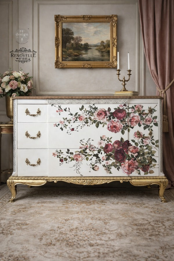 Rich, romantic, and undeniably captivating, Scarlet Embrace features a lush arrangement of blooming roses in deep crimson, soft blush, and warm ivory tones. With its graceful composition and painterly detail, this design evokes timeless elegance—perfect for adding a bold yet refined floral statement to any piece. transfer on the front of a white dresser with gold legs