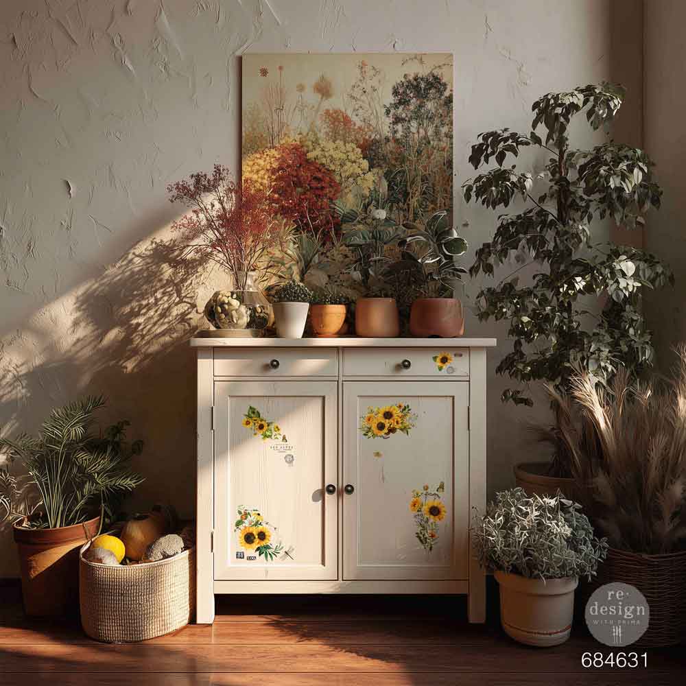 White cabinet with sunflower decals in a room with plants and a floral painting on the wall.
