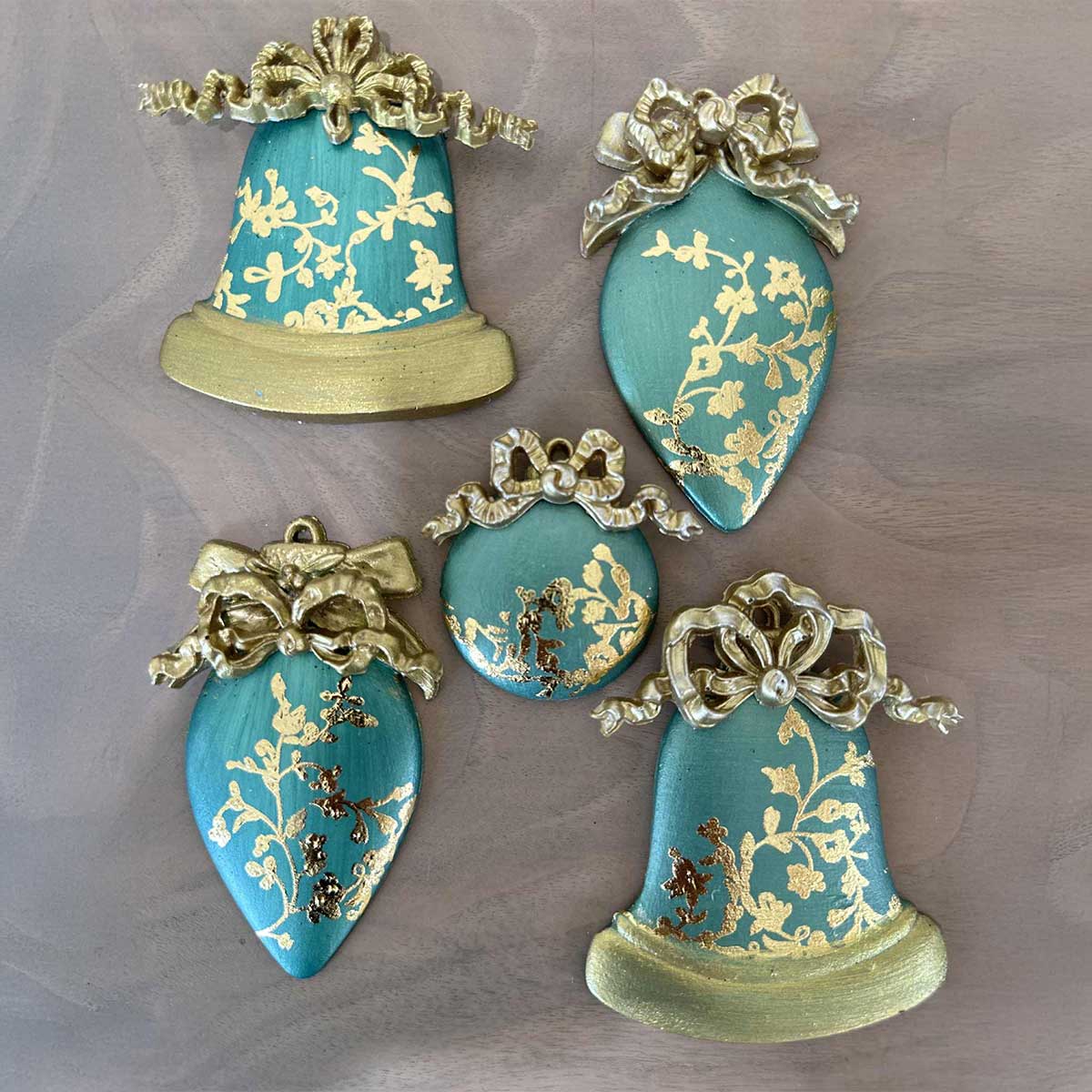 Decorative turquoise bells with gold floral patterns on a gray background