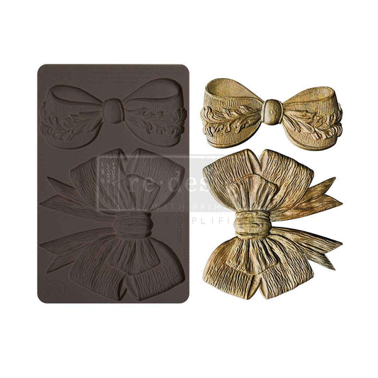 Bow-shaped mold and two gold bow decorations on a white background